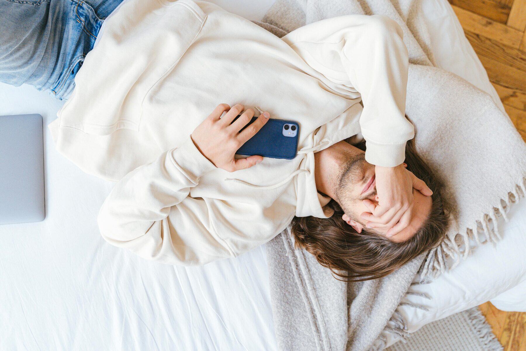 Man with phone, hand covering face — moment of recognition during OnlyFans recovery